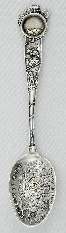 Souvenir Mining Spoon Boise, Idaho.jpg - SOUVENIR MINING SPOON BOISE IDAHO - Sterling souvenir spoon with a figural miner's pan and tools on the end of the handle, spoon measures 5 5/16" long and weighs 0.60 troy ounces, bowl features an embossed view of three men panningfor gold, scene is entitled, "Struck it Rich", bottom of the bowl is engraved "Boise, Idaho",  reverse of spoon is marked with the trademarks for Paye & Baker and "Sterling".  [Boise, the capital of Idaho, had its beginnings in the Idaho gold rush of the early 1860s.  In 1834 Fort Boise, owned by the Hudson Bay Company, was established by British fur traders. The fort, now known as Old Fort Boise, was located at the mouth of the Boise River, 40 miles from present day Boise. In 1854, due to frequent Indian raids, the fort was abandoned. With the discovery of gold in the Boise Basin in 1862, a new Fort Boise was built in 1863 to help protect the influx of gold seekers.  A town site was located next to the fort, and with the protection of the military, the new town of Boise grew quickly.  Its location on the Oregon Trail coupled with routes to the nearby gold mines made Boise a prosperous commercial center.  In 1864 the territorial legislature incorporated Boise and made it the capital of the Idaho Territory.  With Idaho statehood in 1890, Boise became the state’s capital.  Placer deposits of gold were first discovered about 25 miles northeast of Boise in 1862 and soon additional deposits, including significant numbers of lodes, were found covering the mountainous land known as the Boise Basin.  Boise Basin was divided into several mining districts and it covered an area of 300 square miles.  Some of the most notable districts were Idaho City, Moore Creek, Centerville, Quartzburg, Pioneerville and Grimes Pass.  All these districts and deposits yielded over 2,800,000 ounces of gold between the years of 1863 and 1959.  The placer deposits were worked first by large hydraulic washers.  Sometimes entire hillsides were washed away.  Lode work was more erratic and less dependable; miners would work lodes for a few years until another fresh deposit was discovered in a different mining district within the Boise Basin and they would pull up stakes and move on.  Mill sites worked in a similar way.  Whole operations would be dismantled and reassembled again and again around the Boise Basin.  The height of the boom lasted from 1863 to 1866. By 1867 many sold out to Chinese miners who were able, through industrious work, to make the mines pay.  Quartz mining prospered in the 1870s with a number of stamp mills in operation.   Dredge mining began in 1898 and continued till the 1950’s. The Boise Basin was the richest gold strike ever seen in America.  More gold was taken out of the land during this rush than the California 49er or the Klondike gold rush – it’s estimated that more than $250,000,000 was taken from this area in the two decades following its discovery.]  
